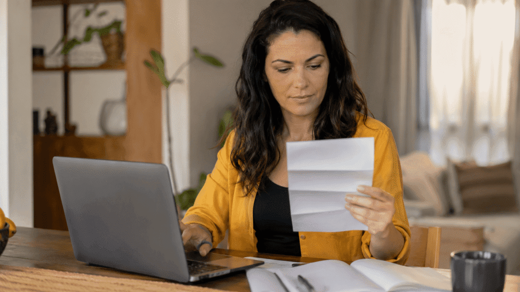 Mulher consultando o IPTU de um imóvel em Guarulhos com um boleto e um notebook em casa