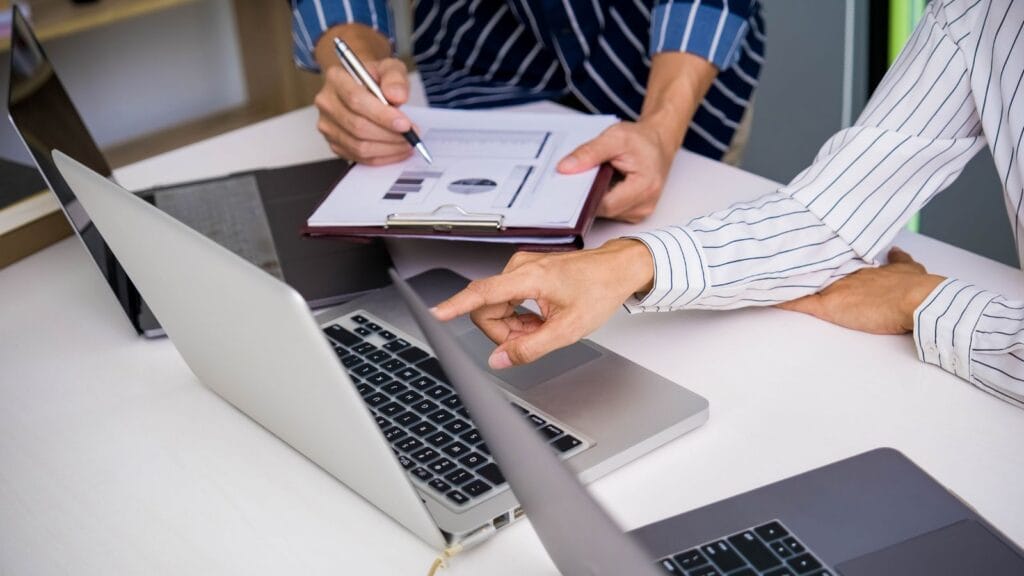 Duas pessoas analisando cálculos e gráficos do reajuste do aluguel no notebook